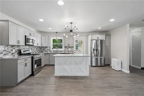 a large kitchen with stainless steel appliances kitchen island granite countertop a refrigerator and a stove top oven