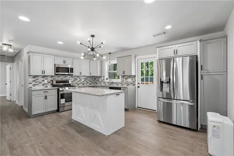 a kitchen with kitchen island white cabinets stainless steel appliances and wooden floor