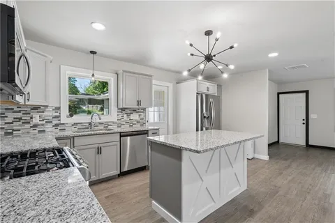 a kitchen with stainless steel appliances a white stove top oven a sink a counter space and cabinets