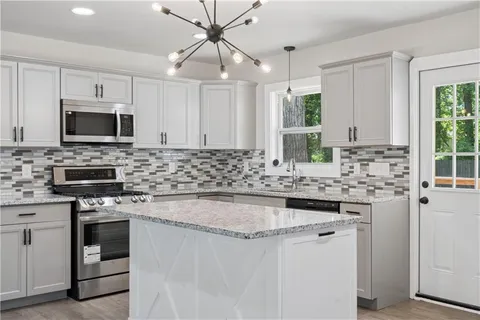 a kitchen with kitchen island granite countertop a stove sink microwave and refrigerator