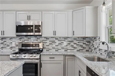 a kitchen with granite countertop a sink stove and microwave