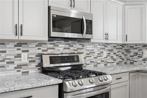 a kitchen with granite countertop a stove sink and microwave