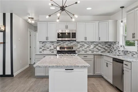 a kitchen with stainless steel appliances granite countertop a sink stove and refrigerator