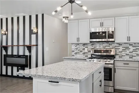 a kitchen with kitchen island granite countertop a stove sink and microwave