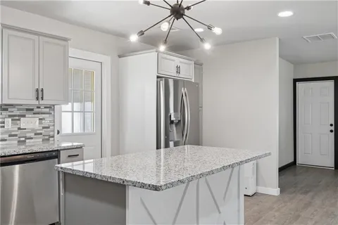 a kitchen with stainless steel appliances granite countertop a sink refrigerator and cabinets