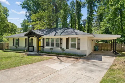 a front view of a house with a garden and trees