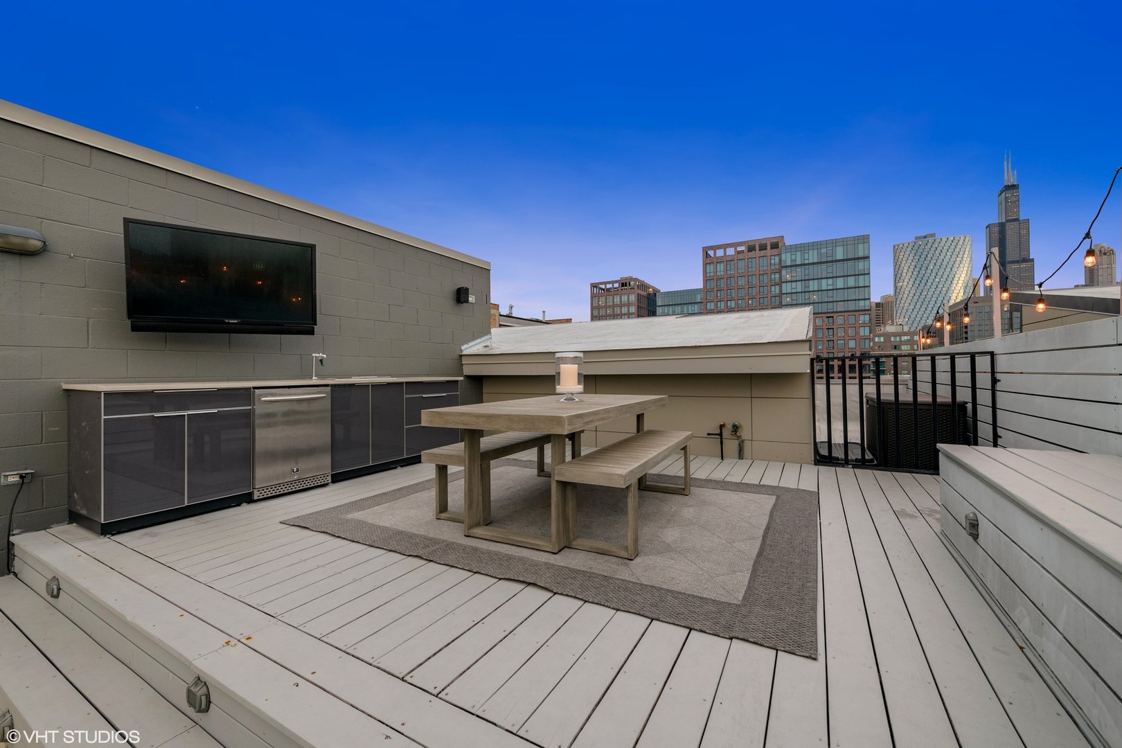 18 North Carpenter Street, Unit PHS Chicago, IL 60607 - Photo 25 of 33 a view of a roof deck with table and chairs with wooden floor and fence