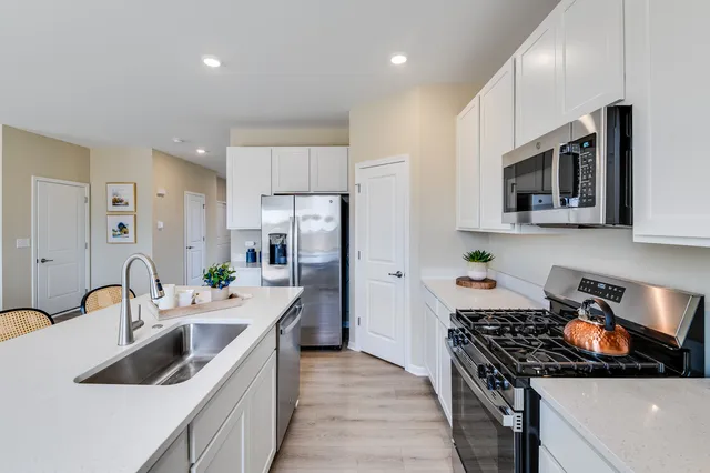 a kitchen with stainless steel appliances granite countertop a sink stove and refrigerator