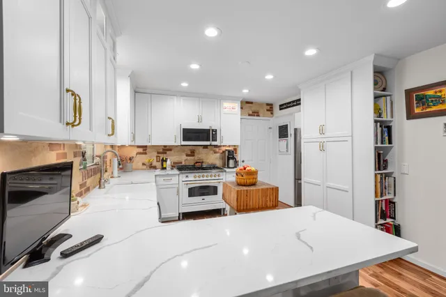 a large white kitchen with stainless steel appliances