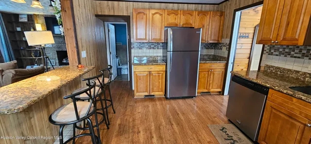 a kitchen with stainless steel appliances granite countertop a refrigerator a stove and a sink with wooden floor