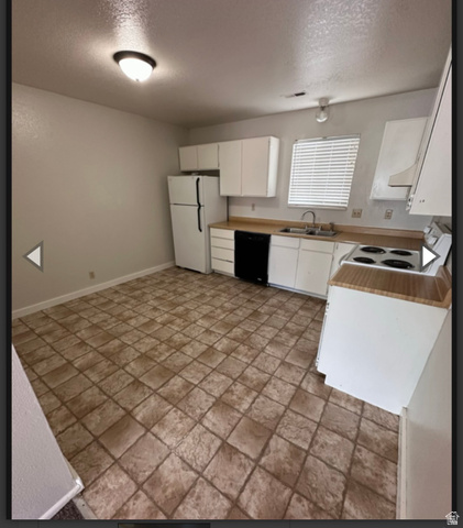 102 East Richelman Lane Wellington, UT 84542 - Photo 29 of 39 Kitchen featuring white cabinets, light countertops, white appliances, a textured ceiling, and light stone finish floors