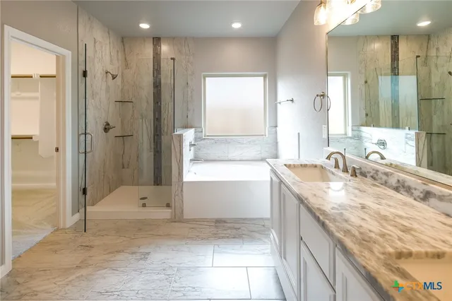 a bathroom with a granite countertop sink a mirror a bathtub and shower