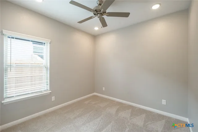 an empty room with a window and a fan