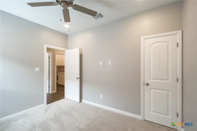 an empty room with a chandelier fan and closet area