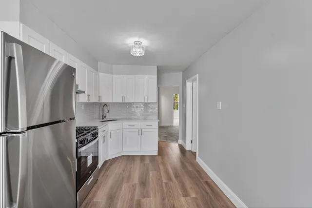 a kitchen with a refrigerator a stove top oven and cabinets