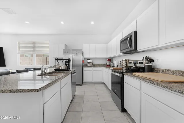a kitchen with stainless steel appliances granite countertop a sink dishwasher stove and white cabinets with wooden floor