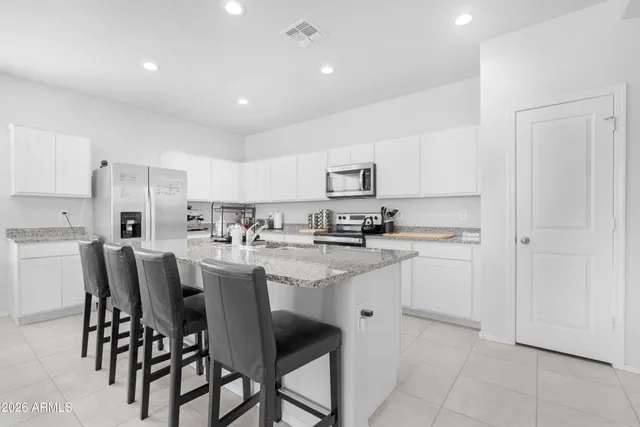 a kitchen with appliances cabinets and chairs