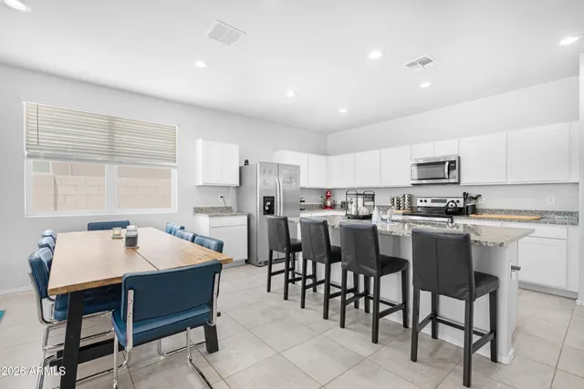 a kitchen with a dining table chairs and refrigerator