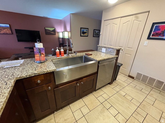 3439 Westwater Road Moab, UT 84532 - Photo 61 of 64 Kitchen with light stone countertops, stainless steel dishwasher, dark brown cabinets, and open floor plan