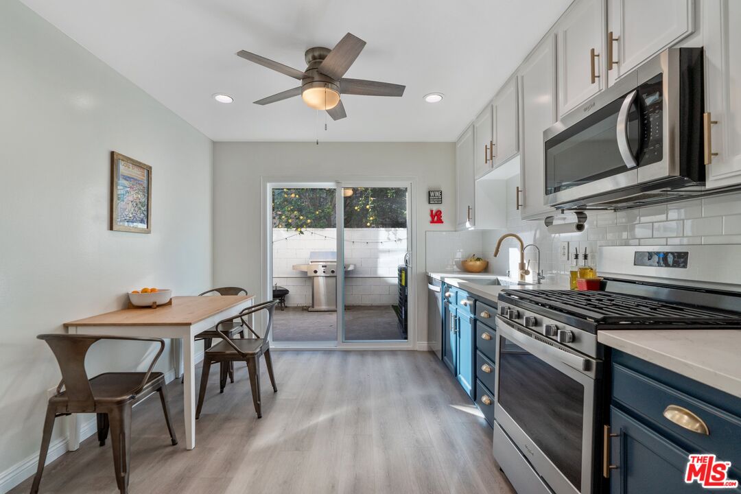 17221 Roscoe Boulevard, Unit 11 Northridge, CA 91325 - Photo 14 of 38 a kitchen with stainless steel appliances a white table chairs and a stove