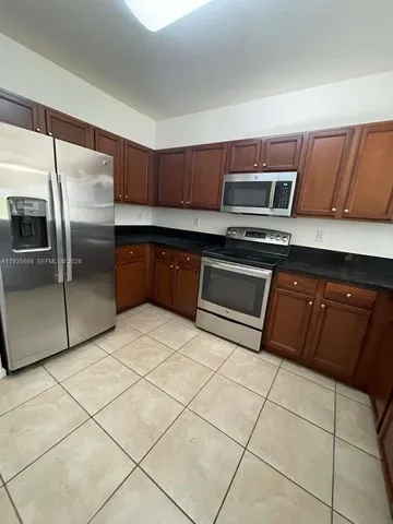 a kitchen with stainless steel appliances granite countertop a sink and a refrigerator