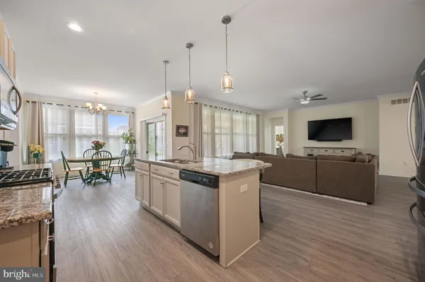 a kitchen with stainless steel appliances granite countertop a stove a sink a microwave a refrigerator a dining table and chairs with wooden floor
