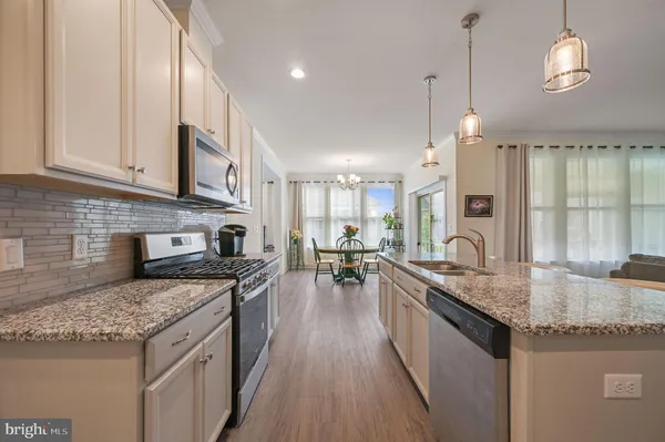 a kitchen with stainless steel appliances granite countertop a stove top oven a sink dishwasher a dining table and chairs with wooden floor