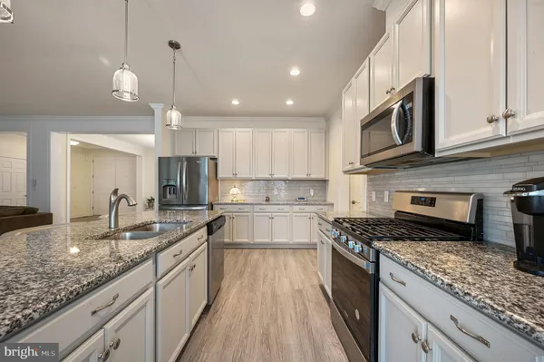 a kitchen with a stove sink cabinets and wooden floor