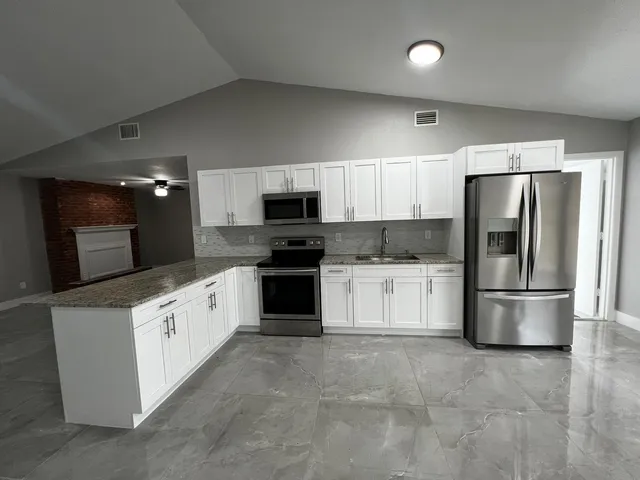 a kitchen with granite countertop white cabinets and stainless steel appliances