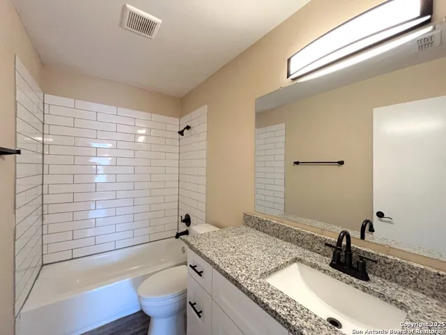 a bathroom with a granite countertop sink toilet and shower