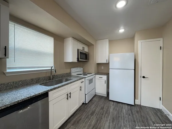 a kitchen with a refrigerator a sink and wooden floors