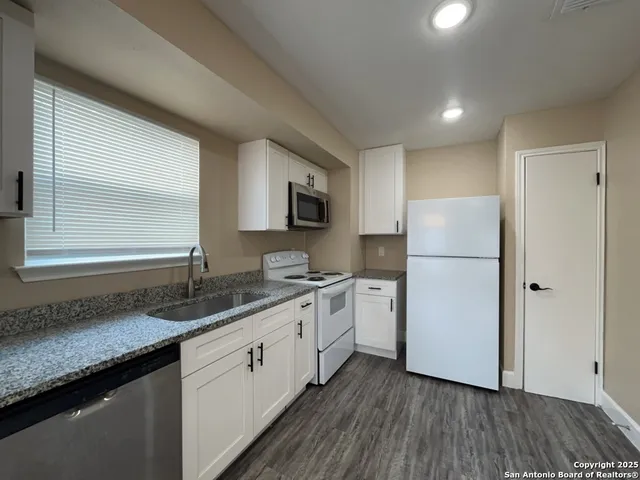a kitchen with a refrigerator a sink and wooden floors