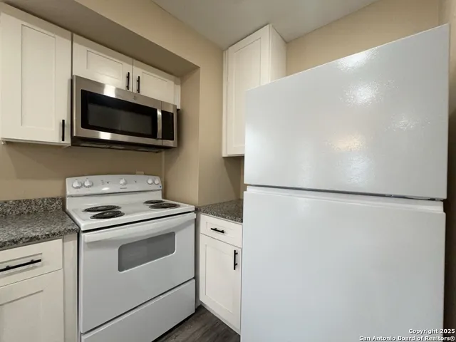 a kitchen with stainless steel appliances white cabinets and a refrigerator