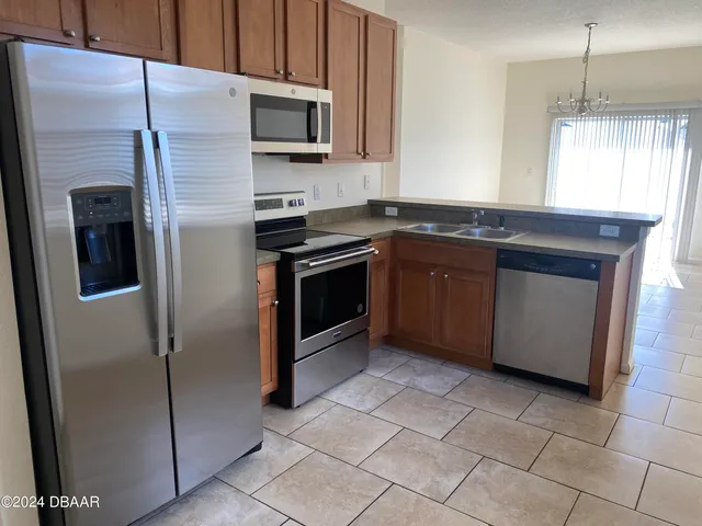 a kitchen with stainless steel appliances granite countertop a refrigerator a sink a stove a microwave and island