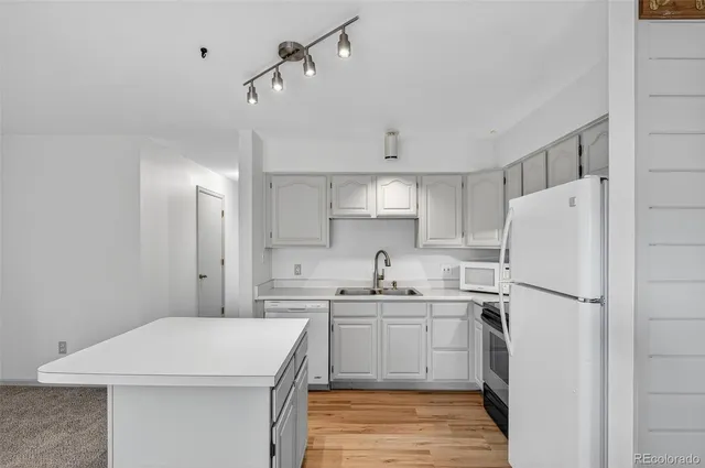 a kitchen with a sink a refrigerator and white cabinets
