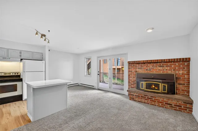 a living room with stainless steel appliances furniture a fireplace and a flat screen tv