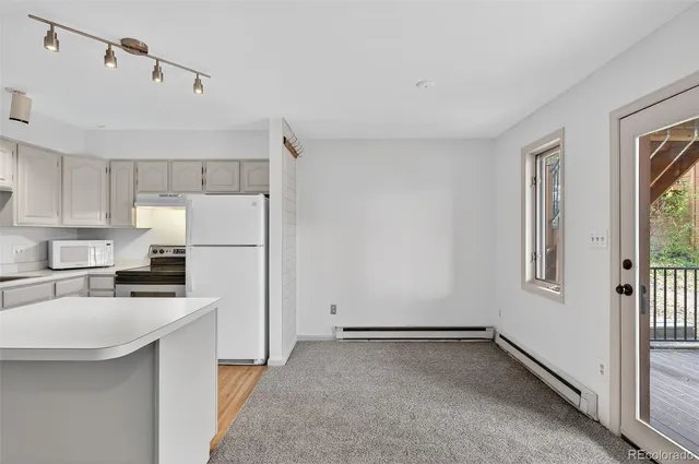 a kitchen with a refrigerator a stove a sink and white cabinets with wooden floor