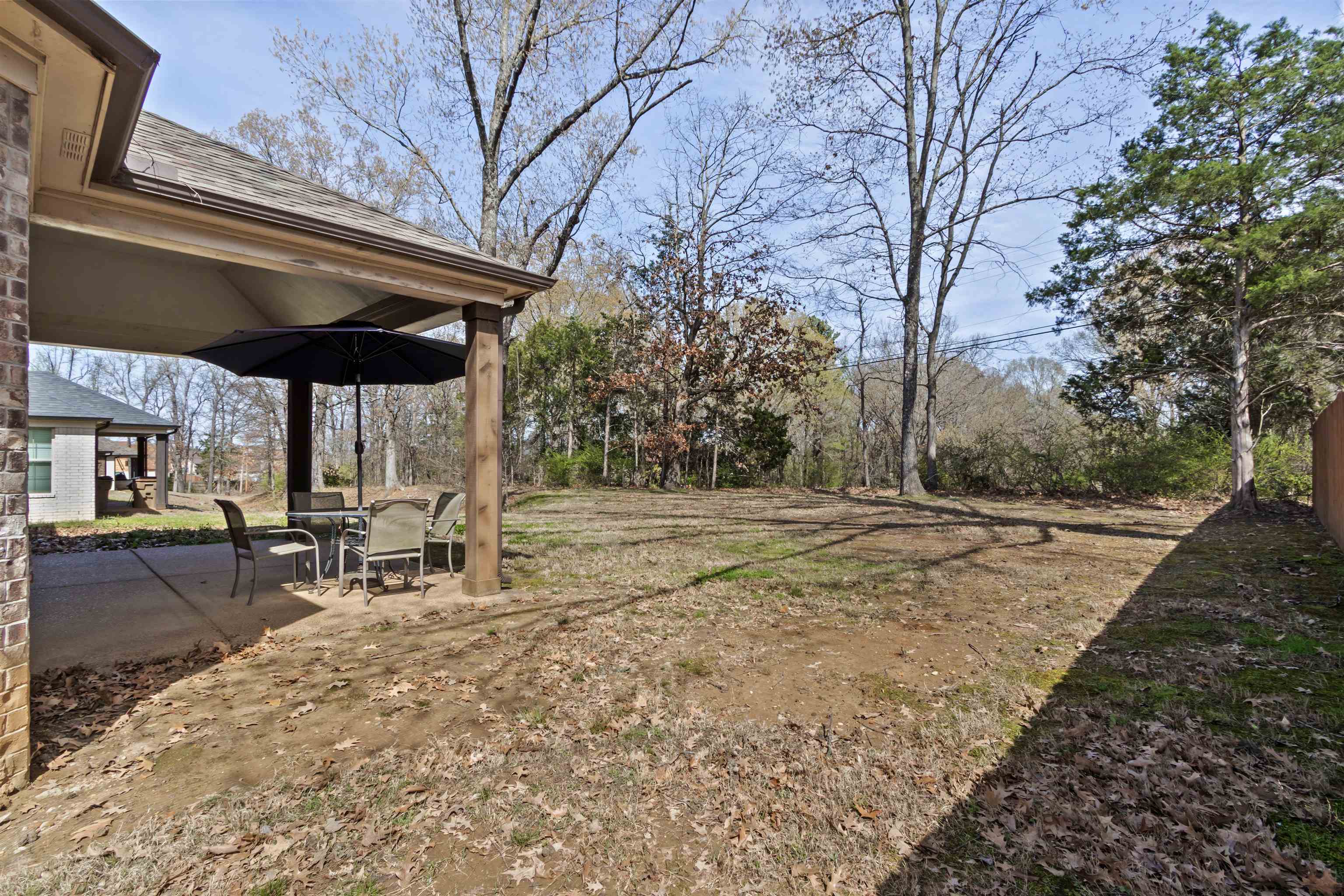 4996 Granite Creek Road Memphis, TN 38125 - Photo 30 of 37 a view of a backyard with table and chairs under an umbrella