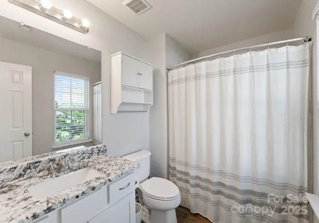a bathroom with a granite countertop sink a toilet and a mirror