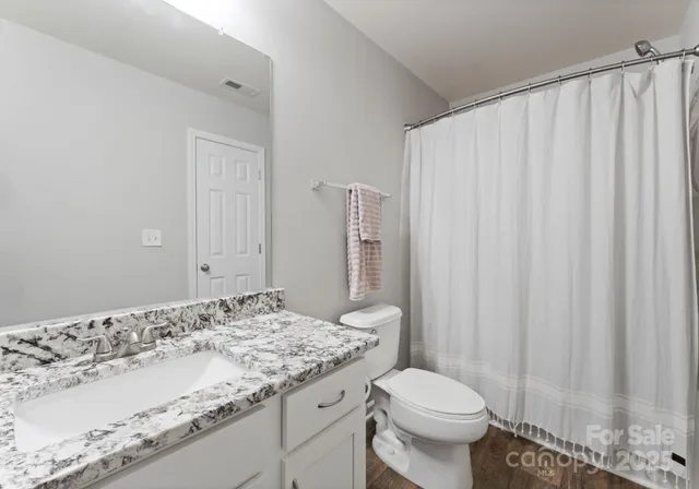 a bathroom with a granite countertop sink toilet and a mirror