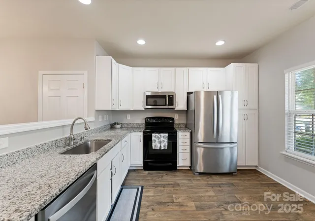 a kitchen with granite countertop a refrigerator sink and microwave