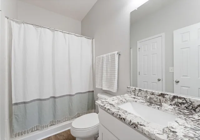 a bathroom with a sink a toilet and shower curtain
