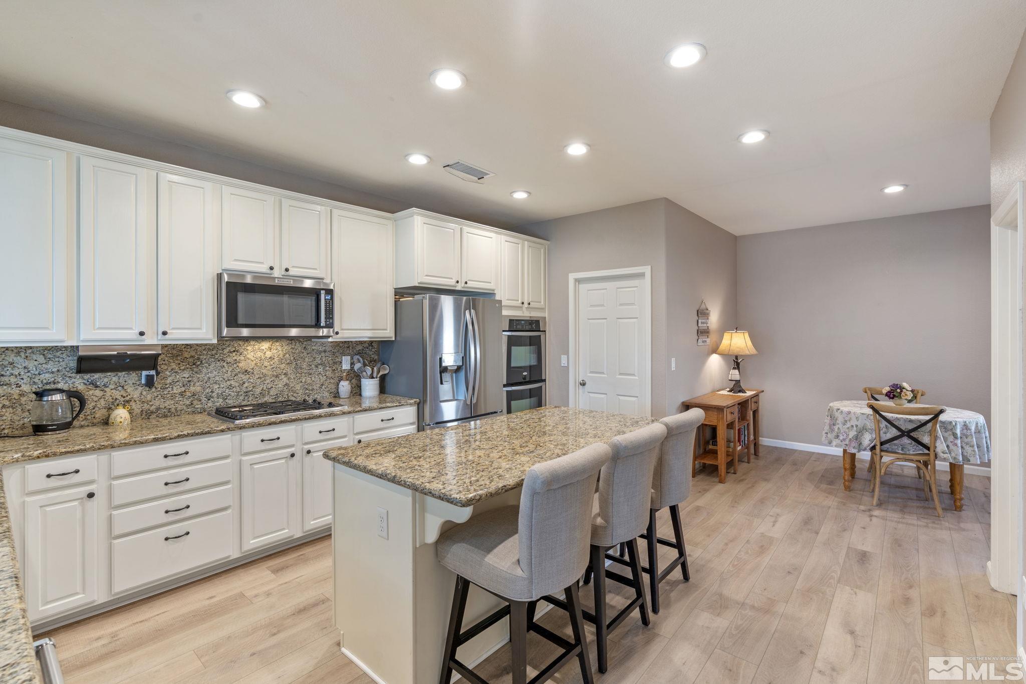 11300 Parma Court Reno, NV 89521 - Photo 19 of 40 a kitchen with stainless steel appliances granite countertop a stove a sink a dining table and chairs
