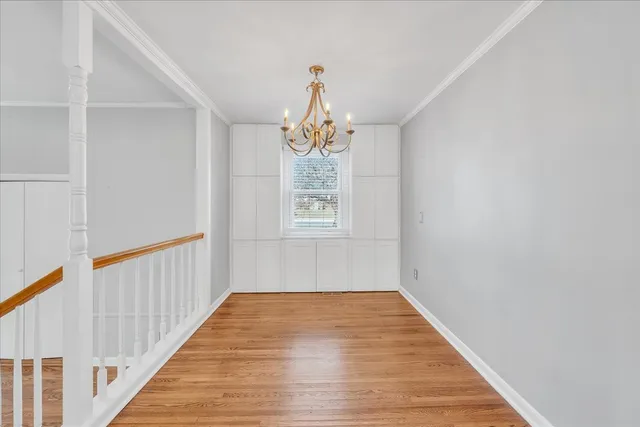 a hallway with wooden floor chandelier and entryway