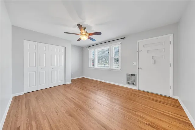 a view of empty room with wooden floor and fan