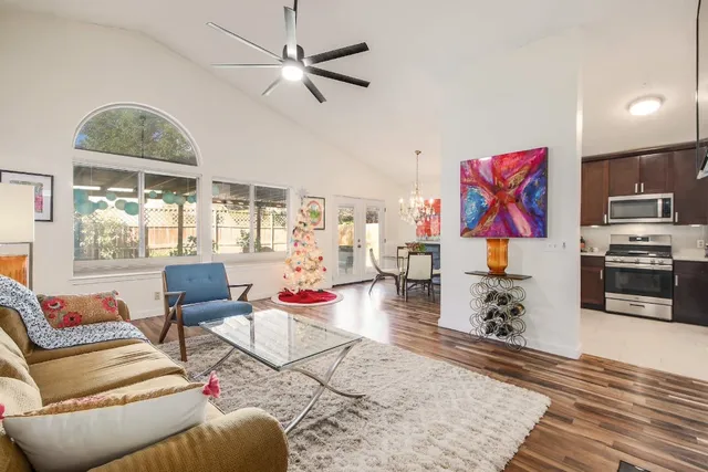a living room with furniture kitchen view and a wooden floor