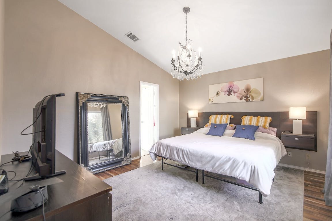 16806 Langland Road Pflugerville, TX 78660 - Photo 7 of 31 a bedroom with a large bed and a chandelier