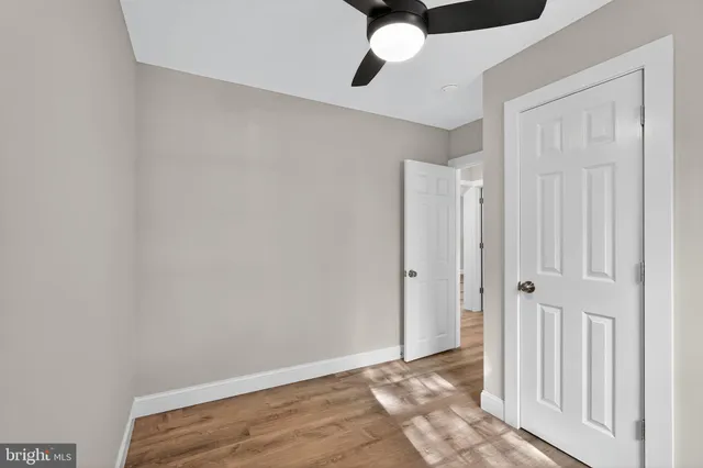 an empty room with wooden floor closet and windows