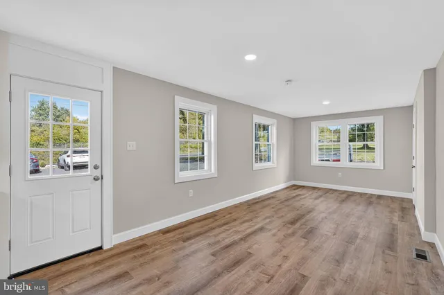 an empty room with wooden floor and windows