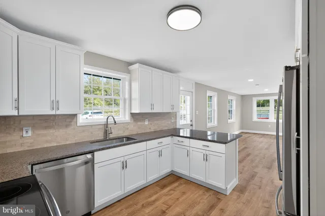 a kitchen with granite countertop a sink stainless steel appliances and cabinets